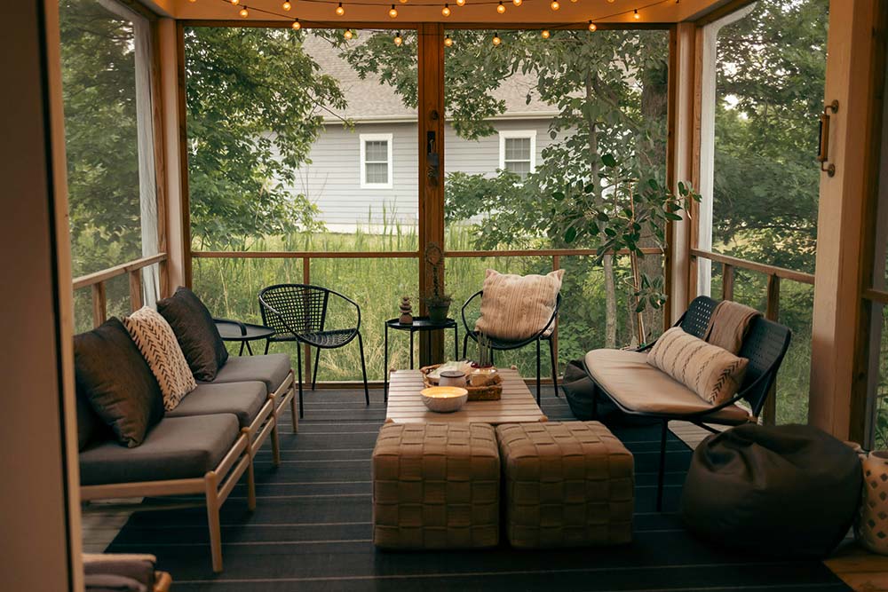 A cozy, screened-in porch decorated in a modern bohemian style.