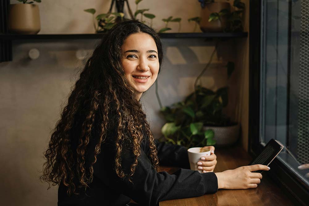 A woman sitting at a table with a cup of coffee