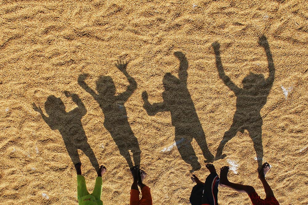 A group of people standing on a sandy beach.
